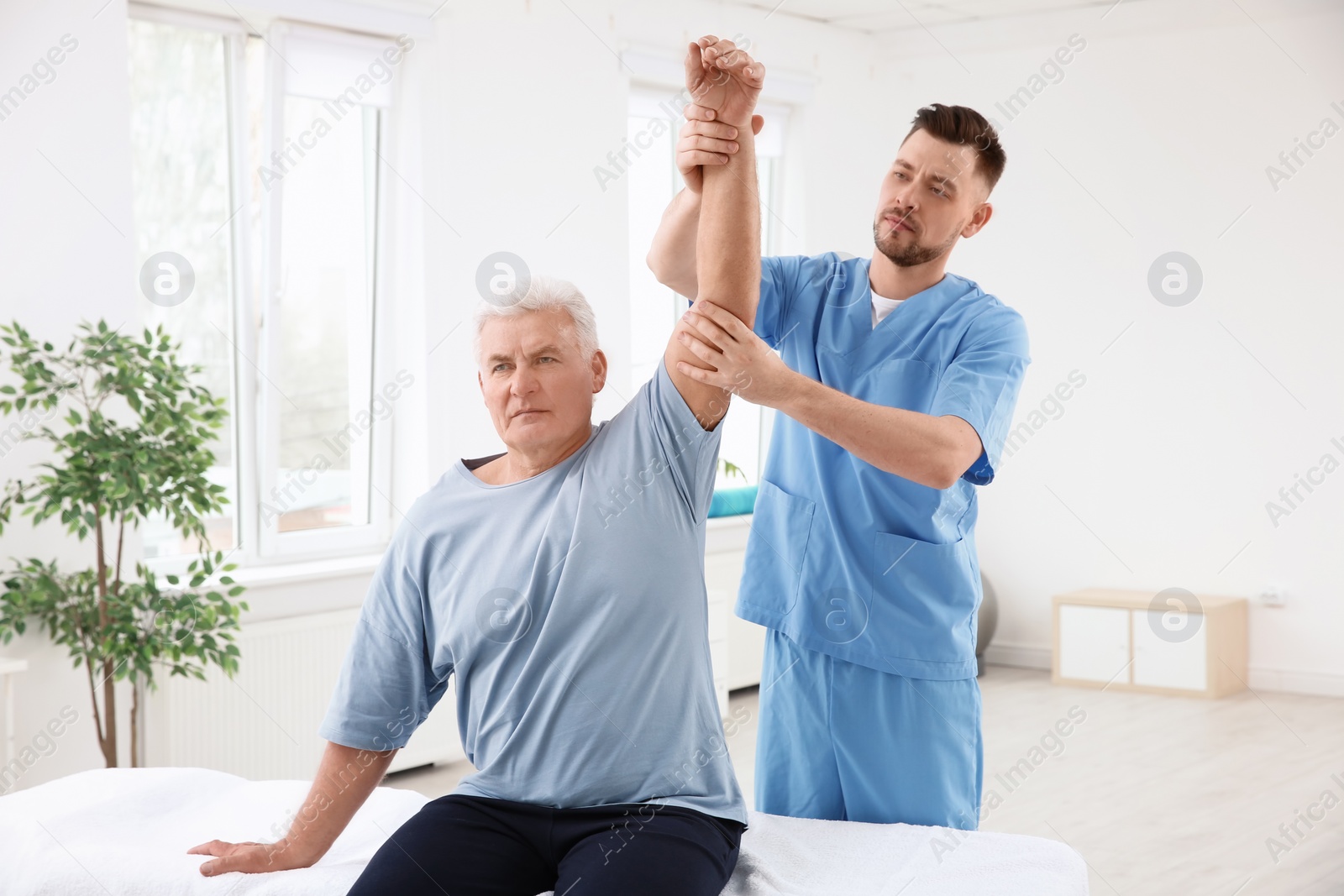 Photo of Young physiotherapist working with senior patient in clinic