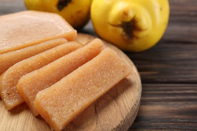 Tasty sweet quince paste and fresh fruits on wooden table, closeup