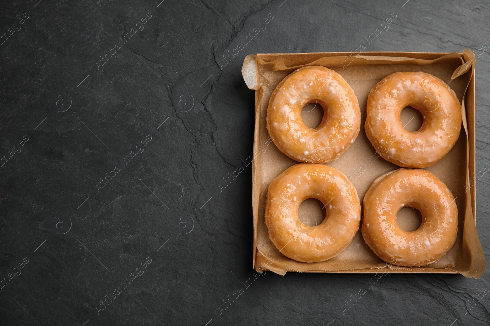 Photo of Delicious donuts on black table, top view. Space for text