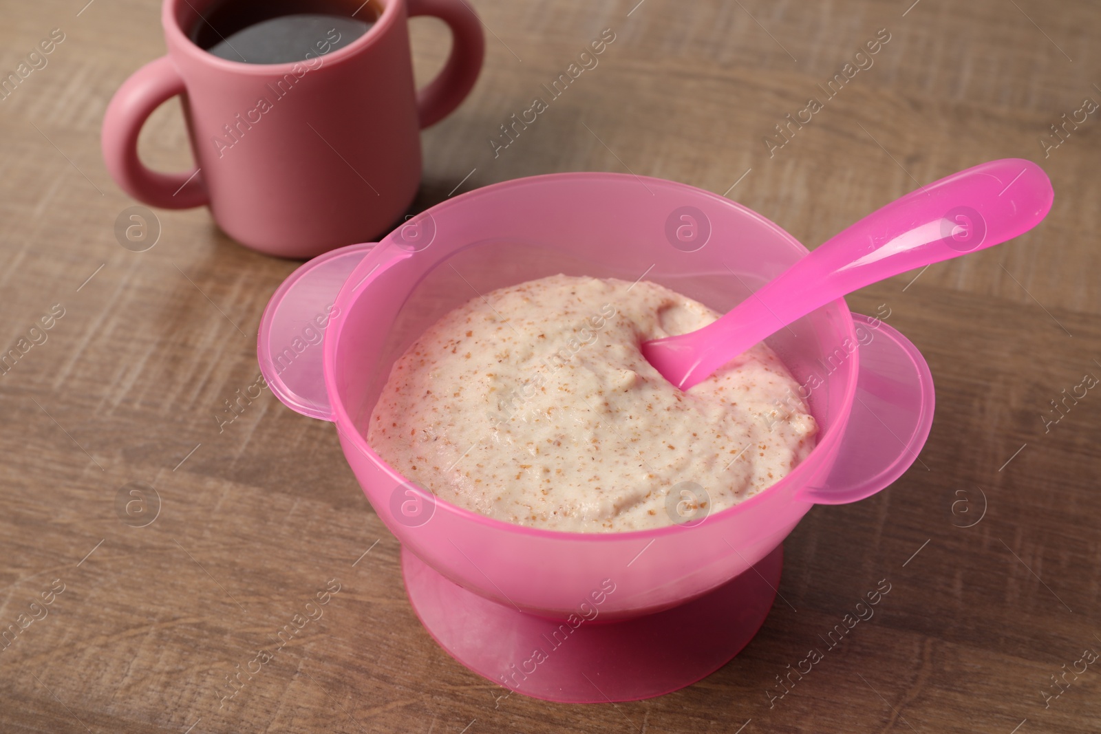 Photo of Baby food. Puree in bowl and drink on wooden table