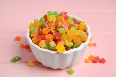 Photo of Mix of delicious candied fruits in bowl on pink wooden table