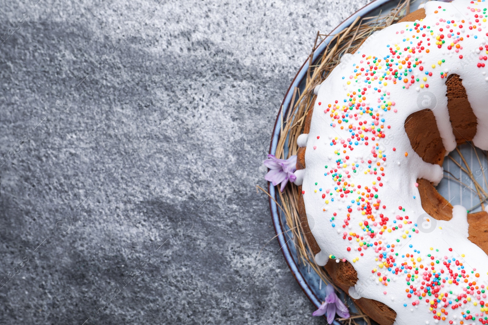 Photo of Glazed Easter cake with sprinkles on grey table, top view. Space for text