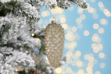 Photo of Beautiful cone shaped bauble hanging on Christmas tree against blurred festive lights, closeup