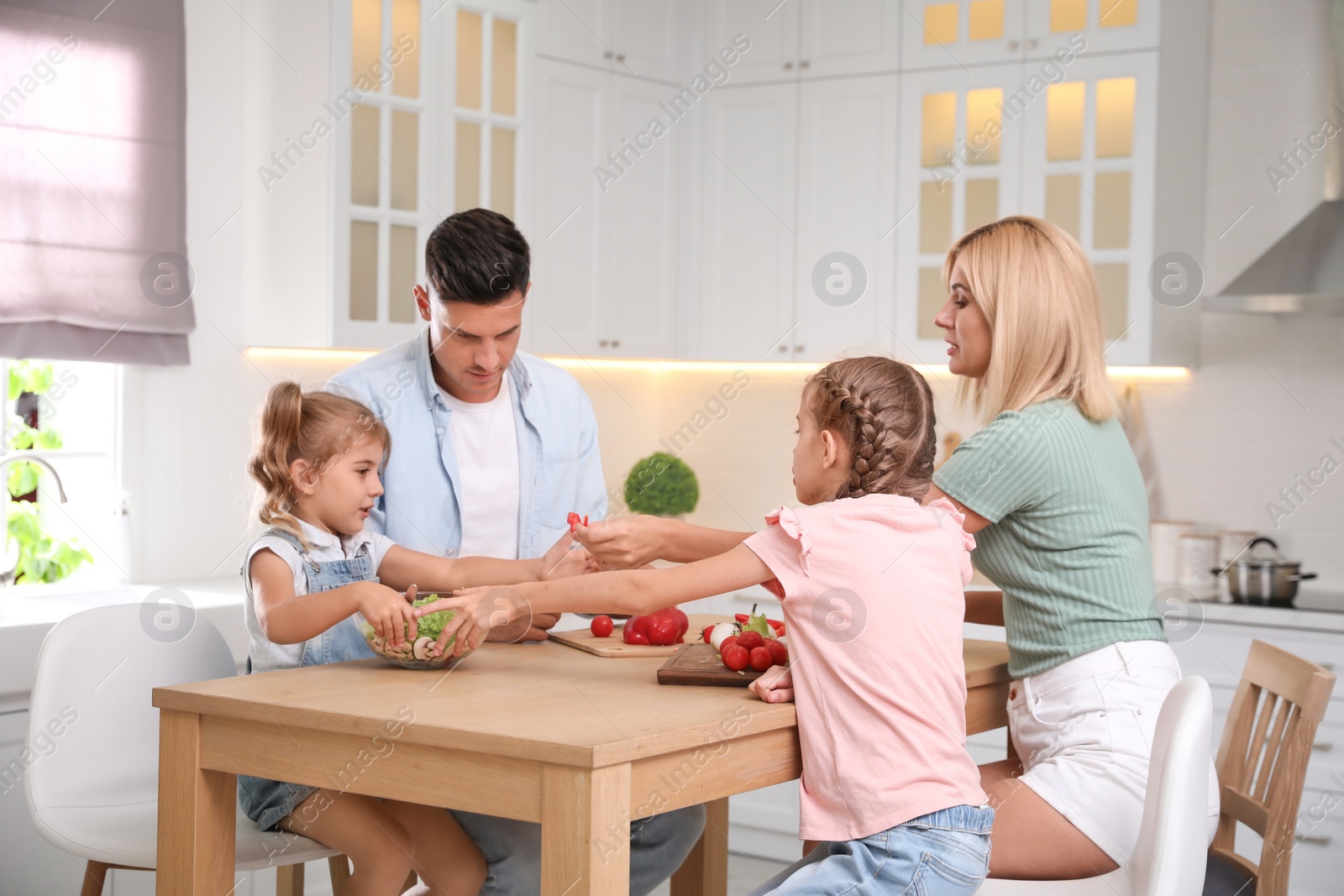 Photo of Happy family cooking together at table in modern kitchen