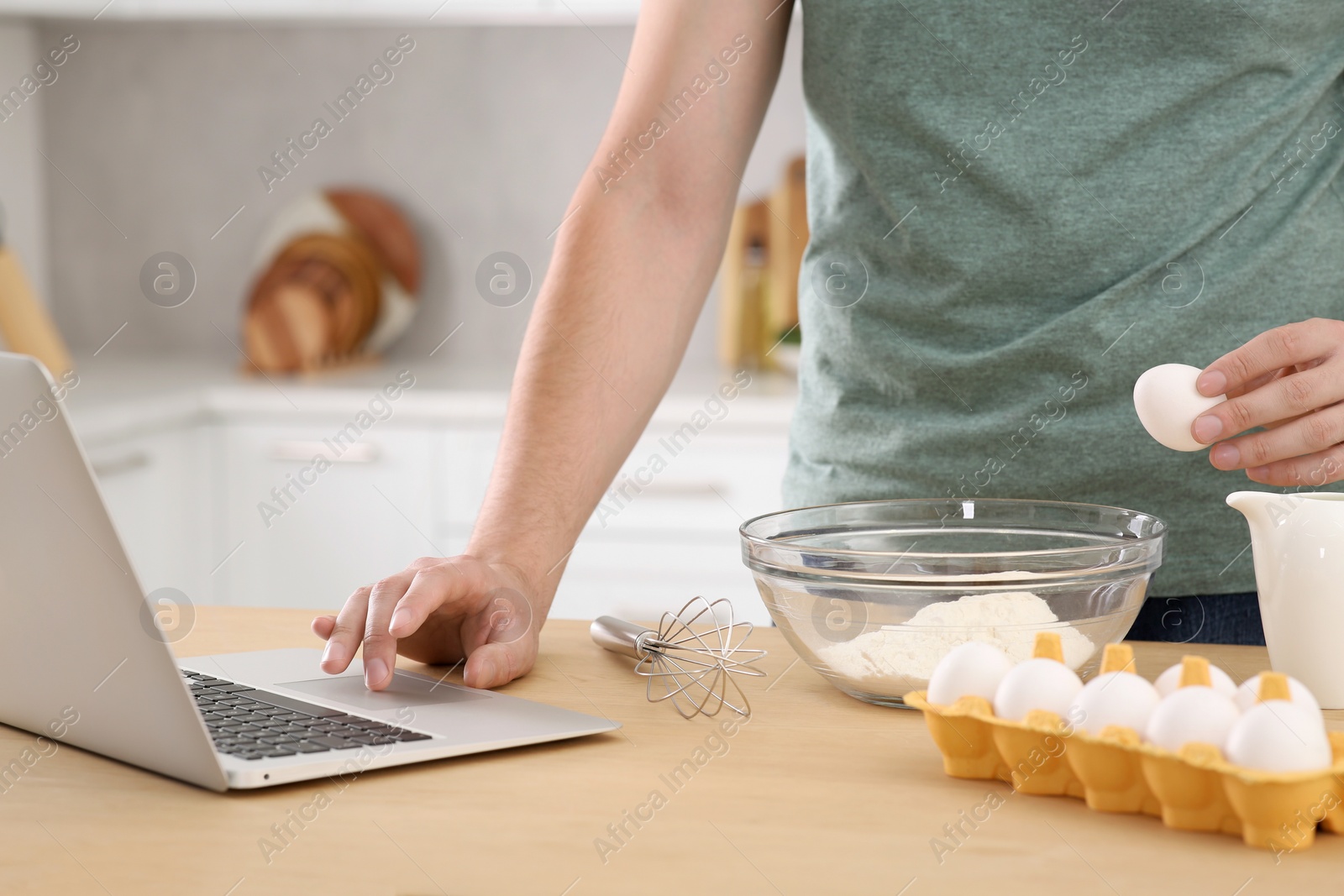 Photo of Man learning to cook with online video at wooden table in kitchen, closeup. Time for hobby