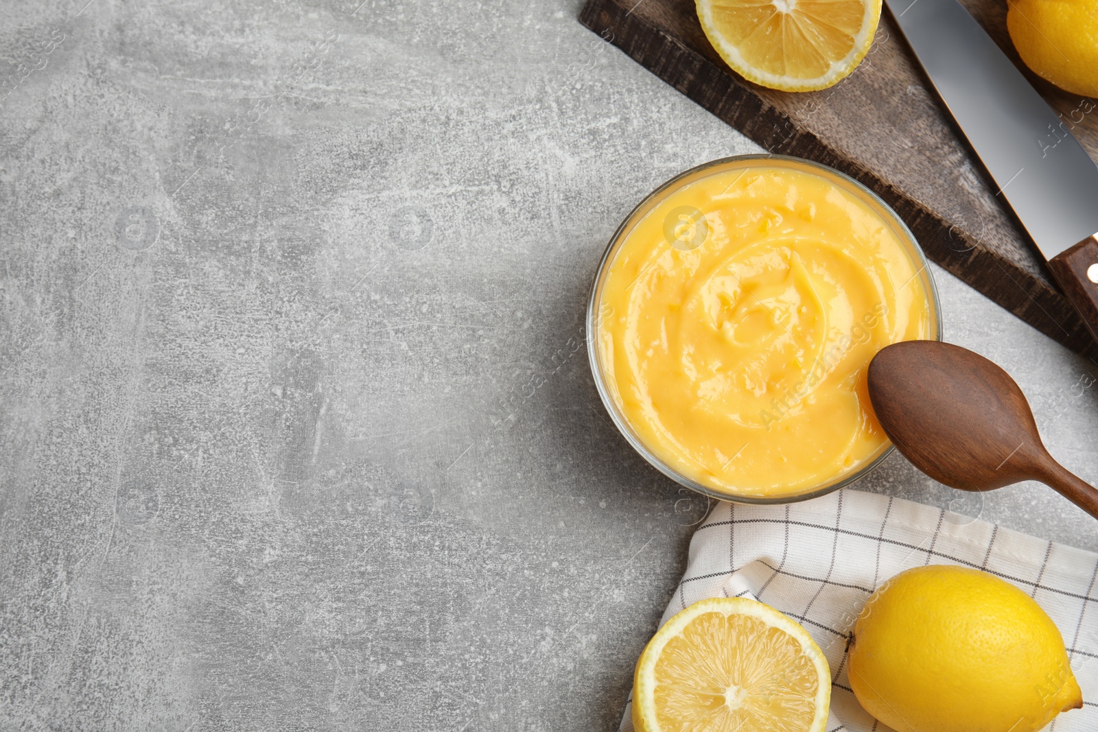 Photo of Delicious lemon curd in bowl on grey table, flat lay. Space for text