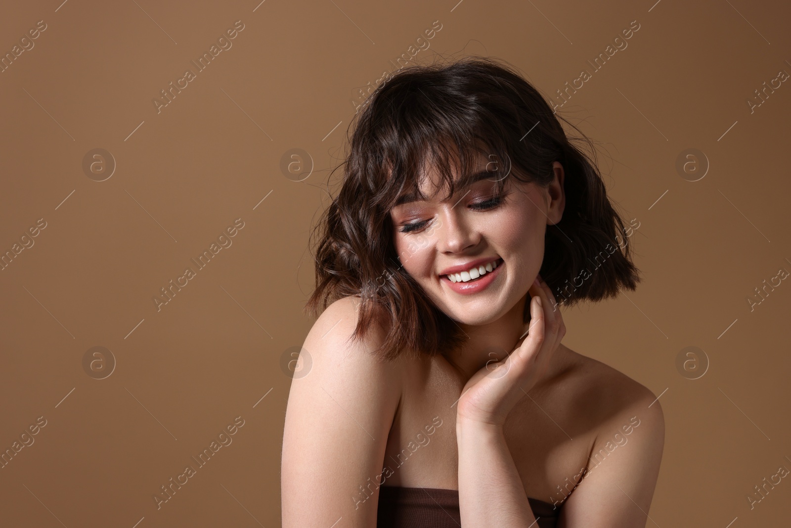 Photo of Portrait of beautiful young woman with wavy hairstyle on brown background. Space for text