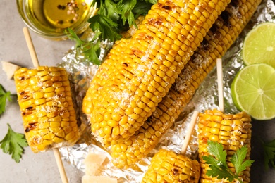 Delicious grilled corn cobs on grey table, flat lay