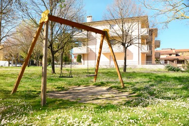 Wooden swings and building on sunny day