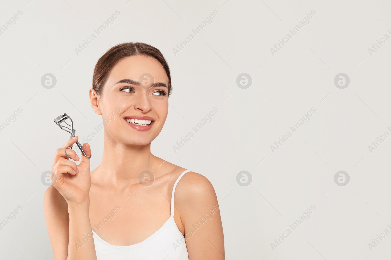 Photo of Woman with eyelash curler on white background, space for text