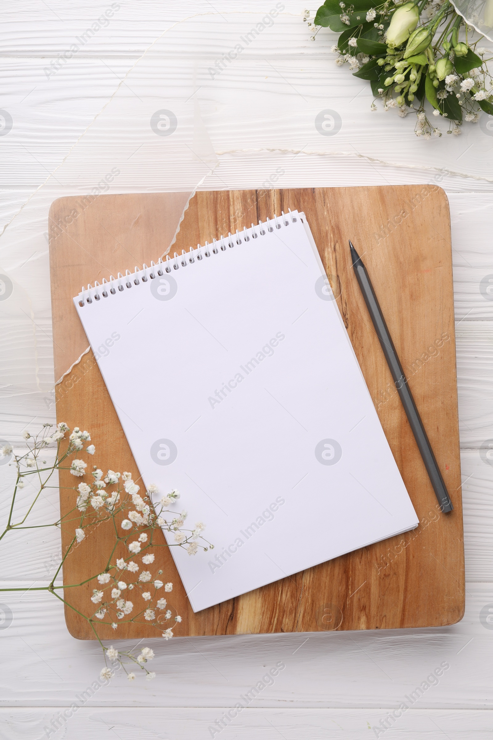 Photo of Guest list. Notebook, pencil, beautiful flowers and ribbon on white wooden background, flat lay