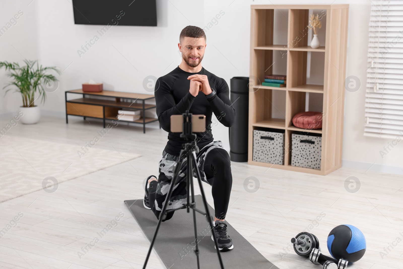 Photo of Trainer streaming online workout with phone at home