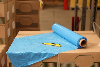 Roll of stretch wrap and utility knife on boxes in warehouse
