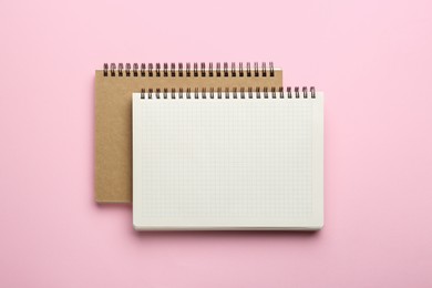 Two notebooks on pink background, top view