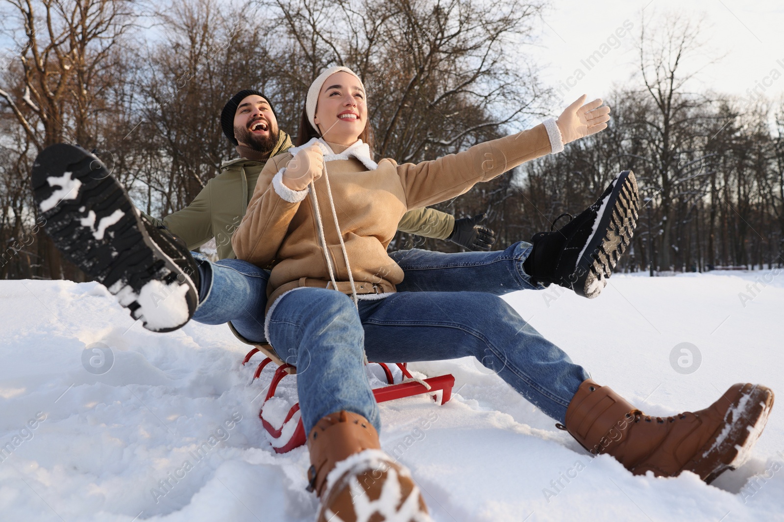 Photo of Happy young couple sledding outdoors on winter day