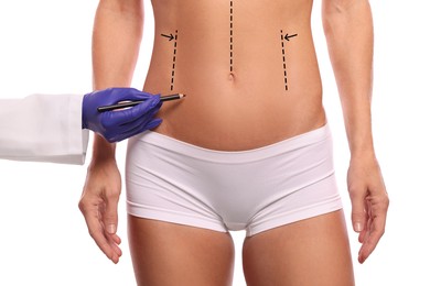 Woman preparing for cosmetic surgery, white background. Doctor drawing markings on her abdomen, closeup