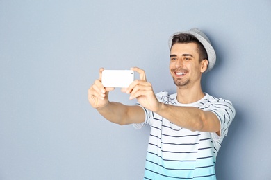 Young handsome man taking selfie against grey background