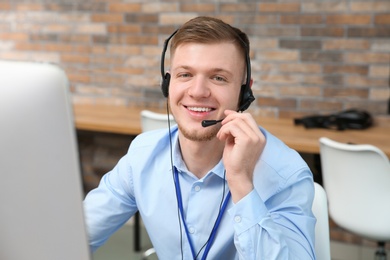 Photo of Technical support operator with headset working in office