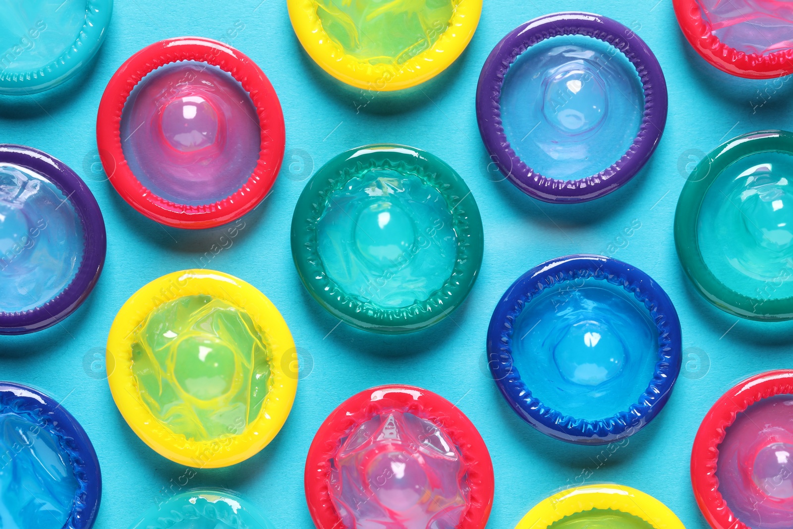 Photo of Colorful condoms on light blue background, flat lay