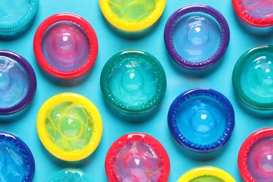 Colorful condoms on light blue background, flat lay