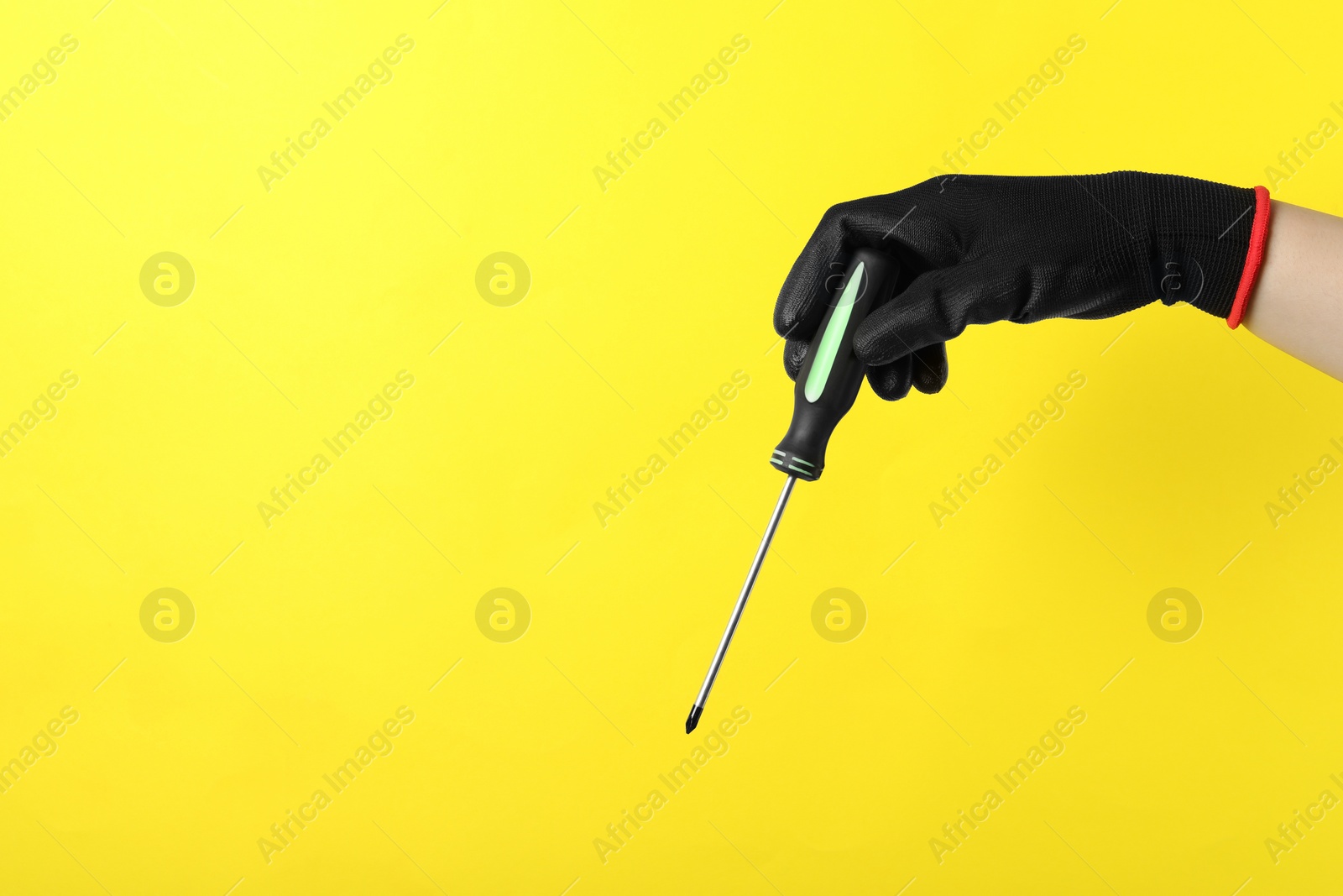 Photo of Woman holding screwdriver on yellow background, closeup. Space for text