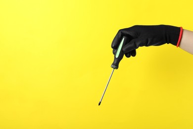 Photo of Woman holding screwdriver on yellow background, closeup. Space for text