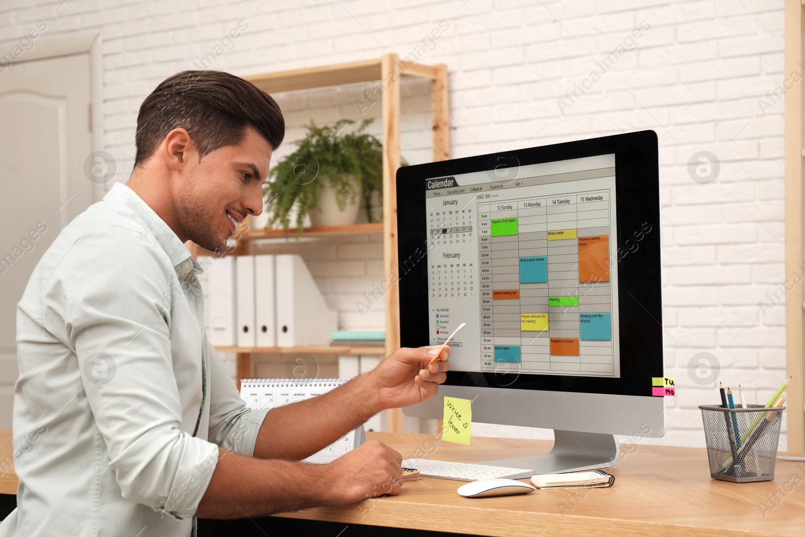 Photo of Handsome man using calendar app on computer in office