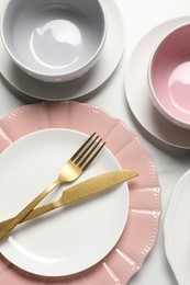 Beautiful ceramic dishware and cutlery on white table, flat lay