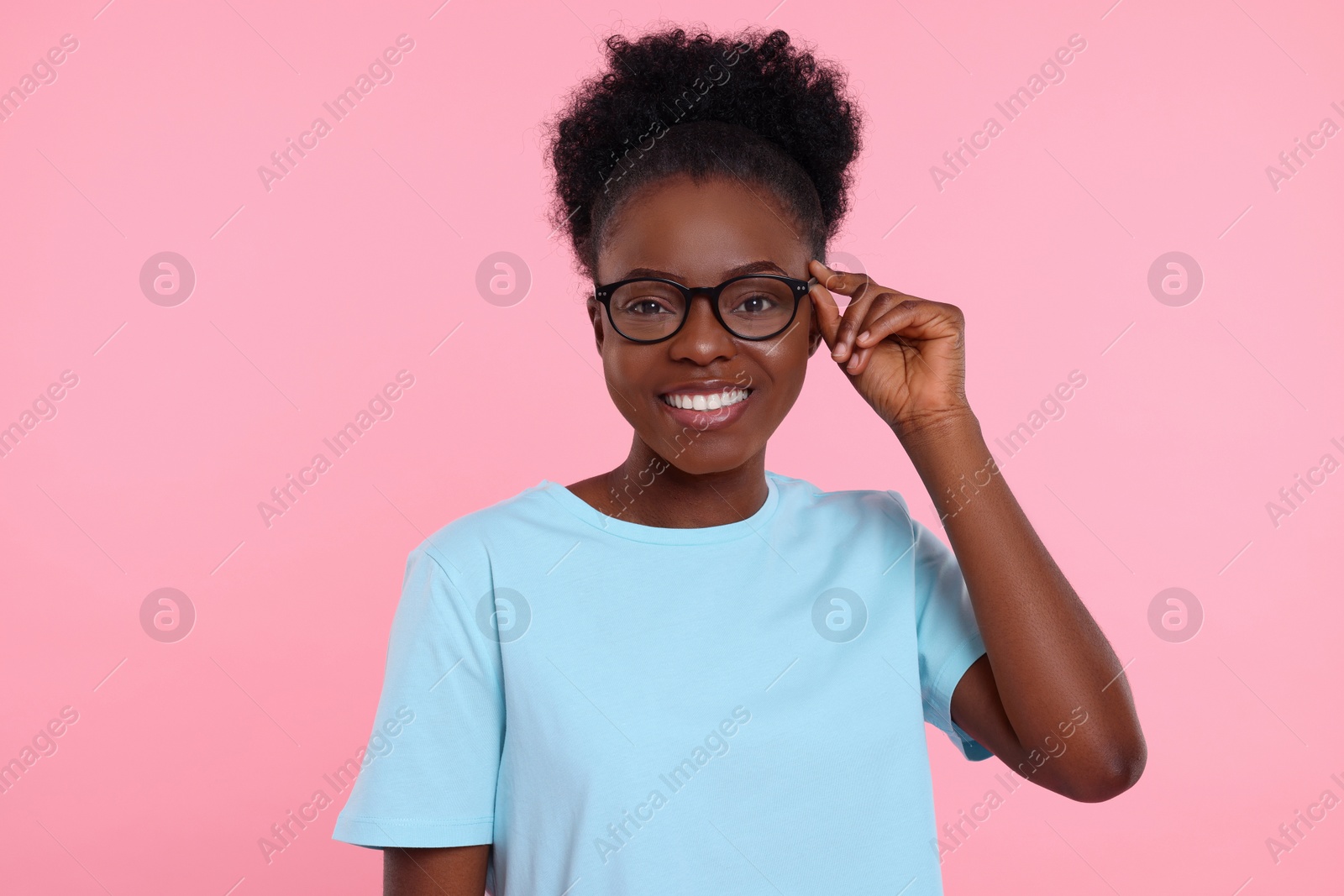 Photo of Portrait of happy young woman in eyeglasses on pink background