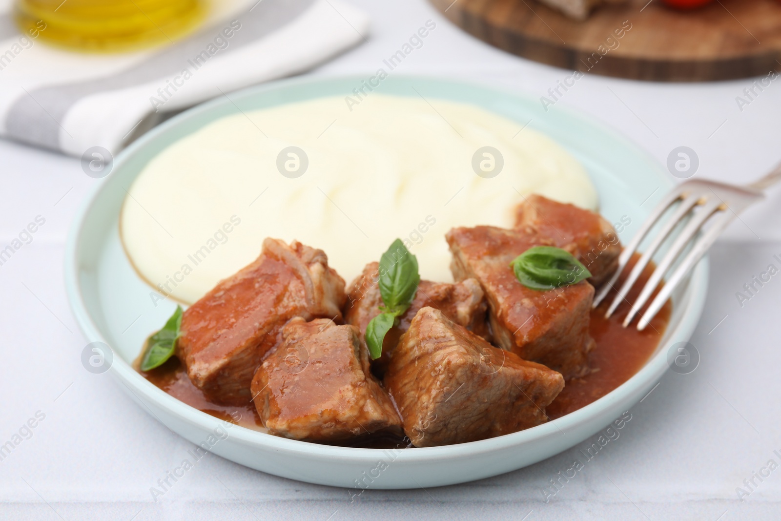 Photo of Delicious goulash served with mashed potato on white table, closeup