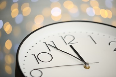 Photo of Clock showing five minutes until midnight on blurred background, closeup. New Year countdown
