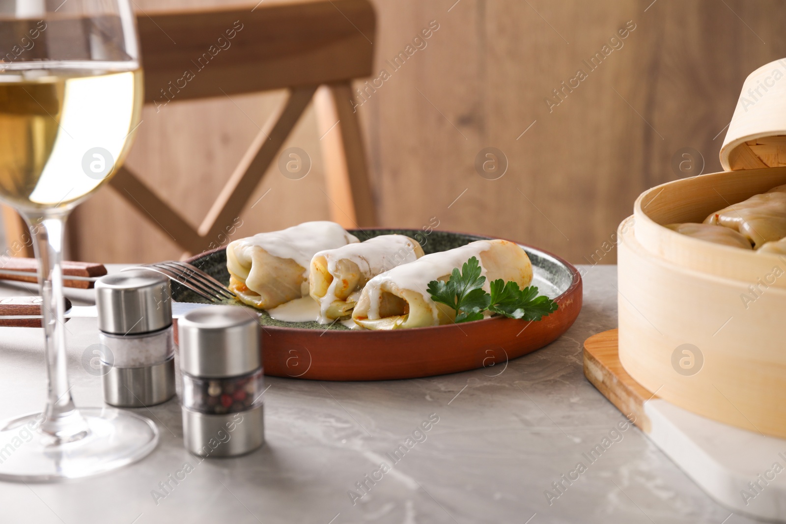 Photo of Delicious cabbage rolls served on grey marble table indoors