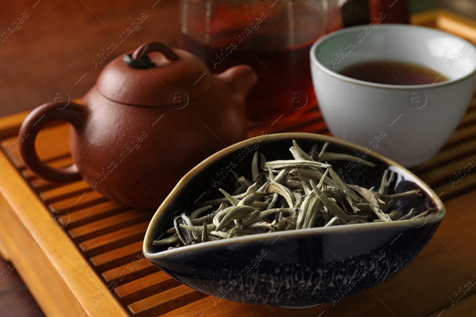 Photo of Aromatic Baihao Yinzhen tea and teapot on wooden tray, closeup. Traditional ceremony