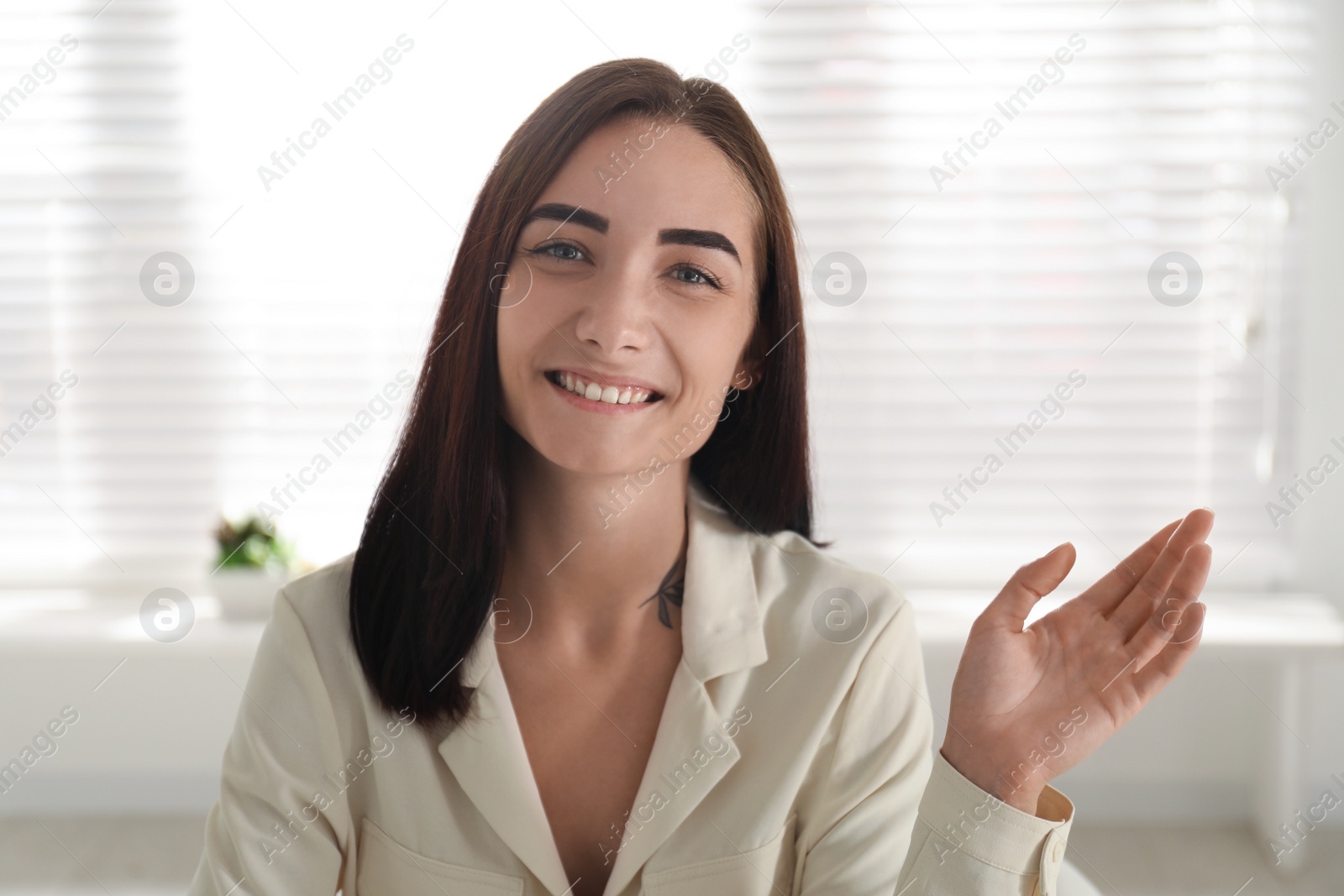 Photo of Young woman talking to her coworkers through video conference indoors, view from webcam