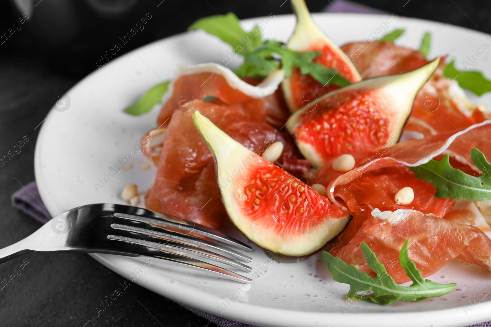 Photo of Delicious figs and proscuitto on plate, closeup