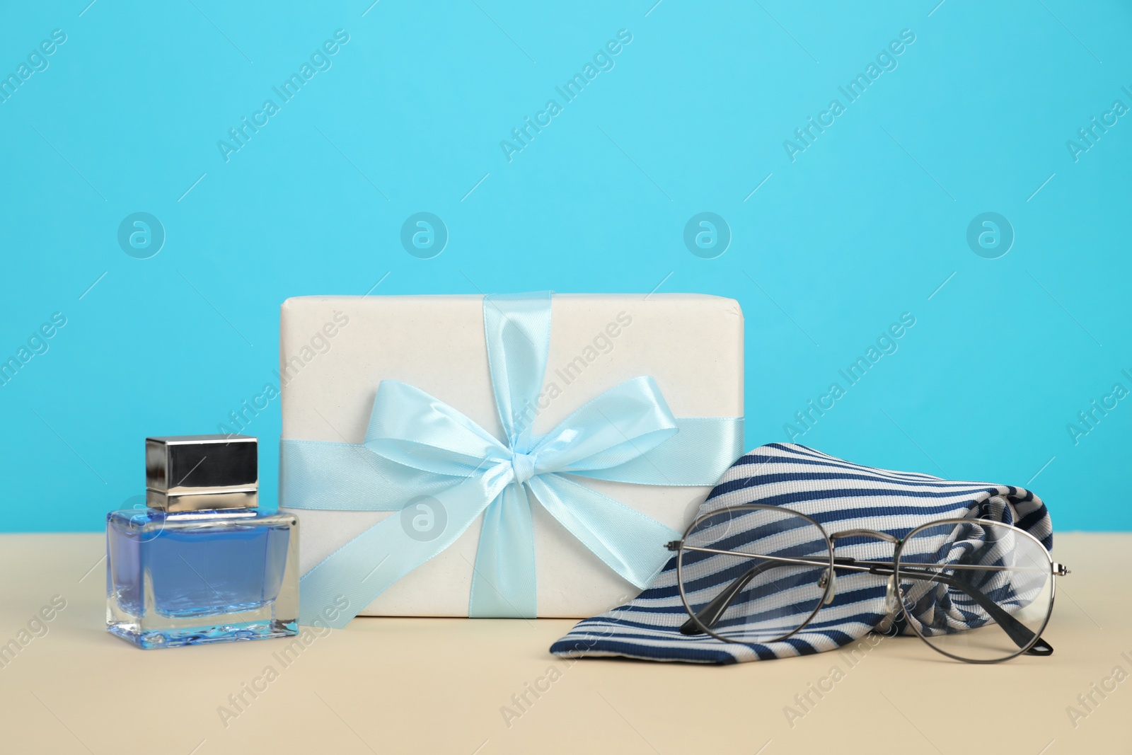 Photo of Happy Father's Day. Tie, glasses, perfume and gift box on beige table