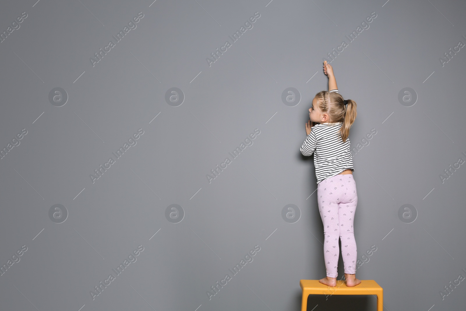 Photo of Little child drawing with colorful chalk on gray background. Space for design