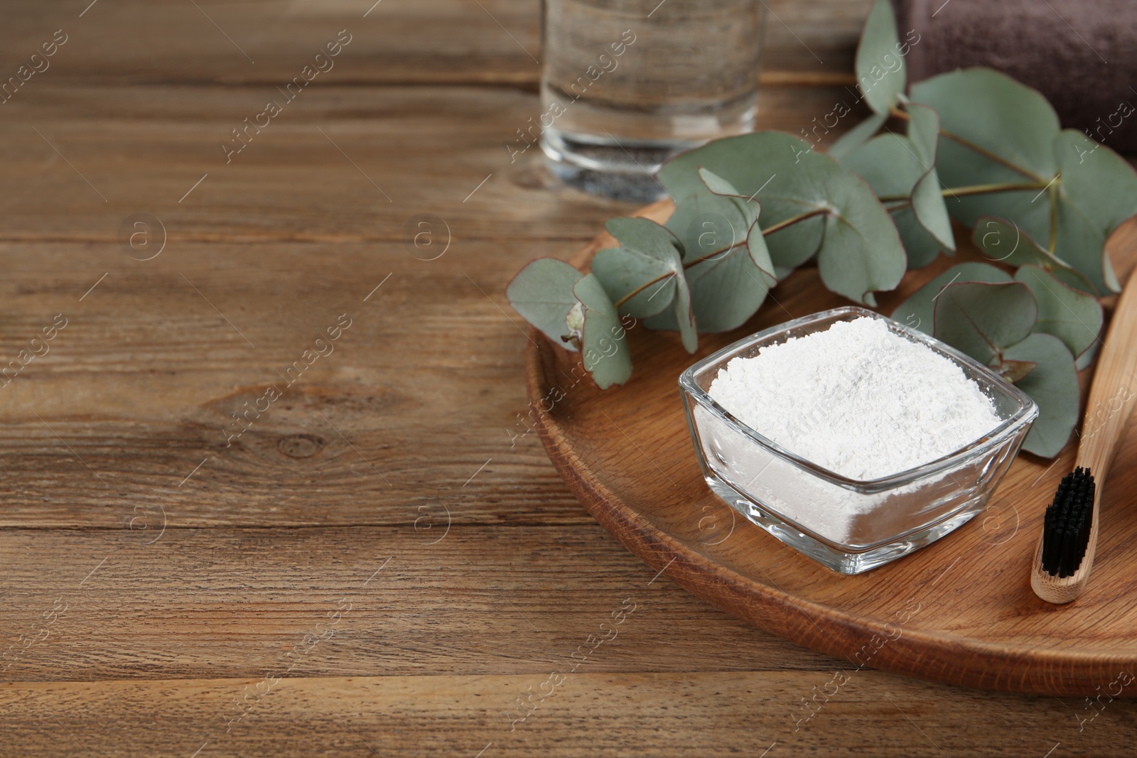 Photo of Tooth powder, brush and eucalyptus on wooden table, space for text