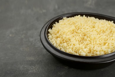 Photo of Bowl of tasty couscous on grey table, closeup. Space for text