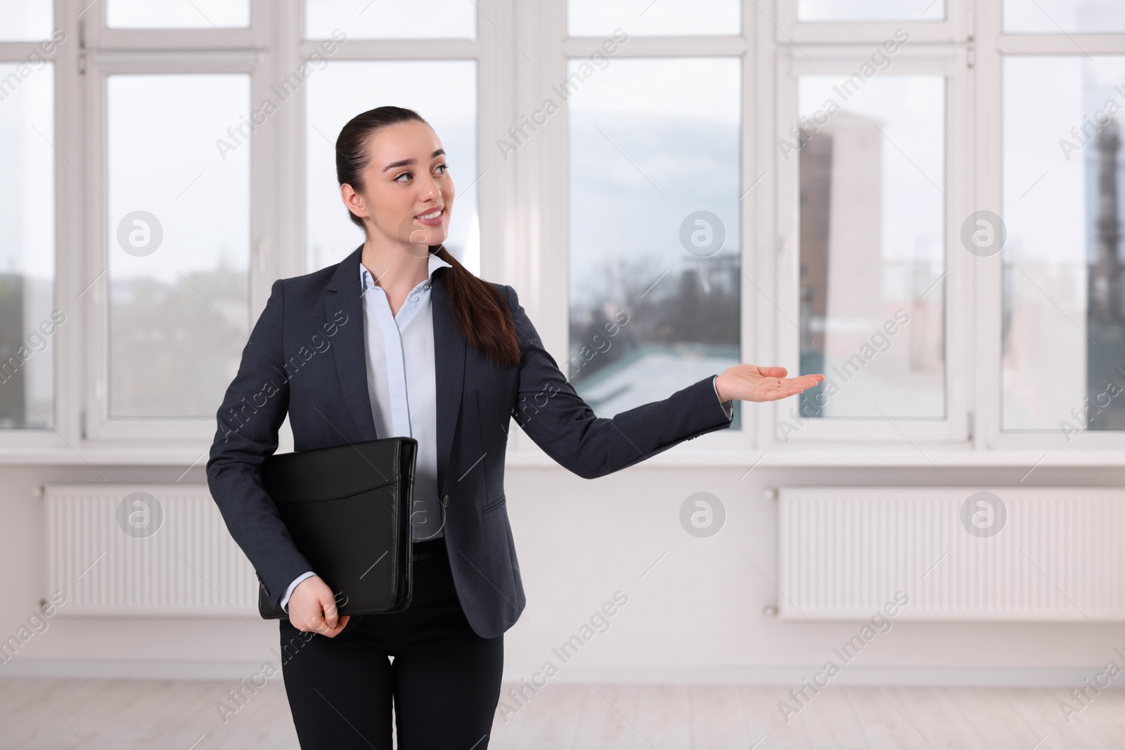 Photo of Happy real estate agent with leather portfolio showing new apartment