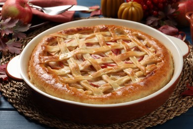 Photo of Delicious homemade apple pie and autumn decor on blue wooden table. Thanksgiving Day celebration
