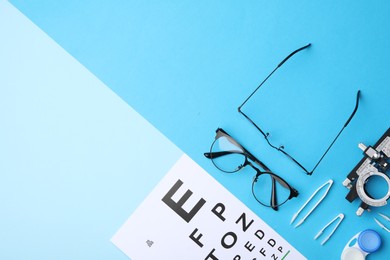 Photo of Flat lay composition with vision test chart and glasses on light blue background, space for text