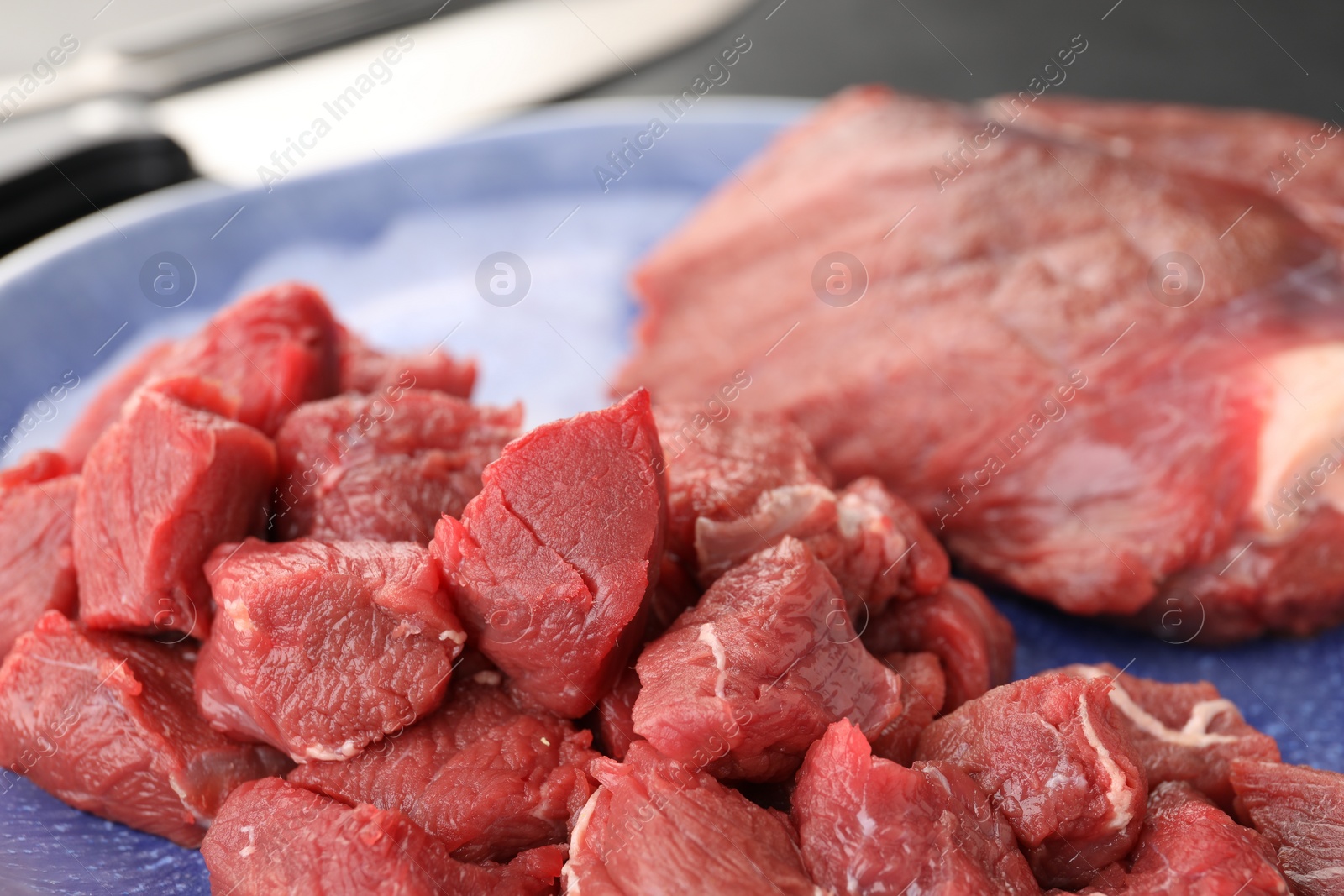 Photo of Plate with pieces of raw beef meat on table, closeup