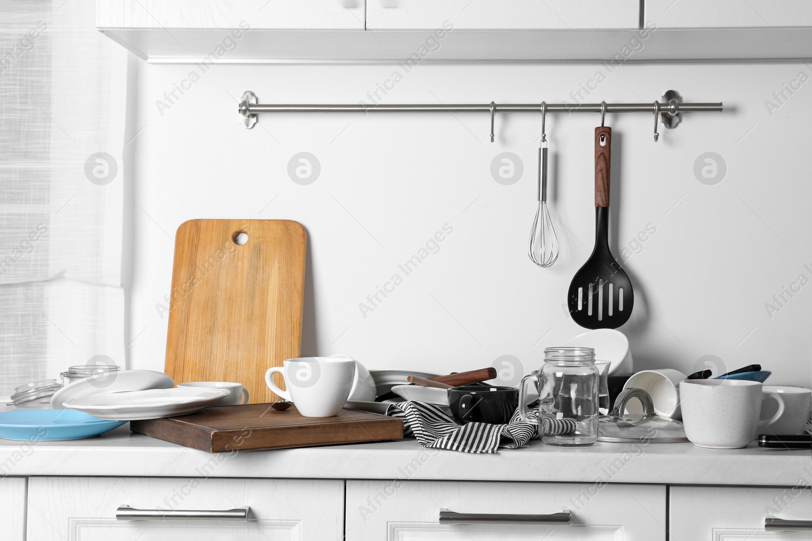 Photo of Many dirty utensils and dishware on countertop in messy kitchen