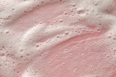 Photo of White washing foam on pale pink background, top view