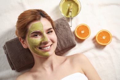Photo of Beautiful woman with mask on face relaxing in spa salon, top view