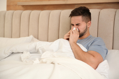 Photo of Sick young man in bed at home. Influenza virus