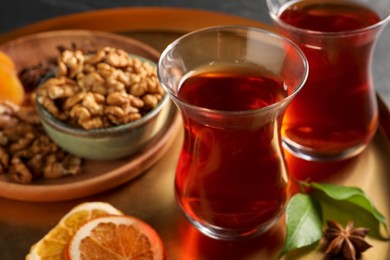 Photo of Tray with glasses of traditional Turkish tea, walnuts, dried orange and anise, closeup