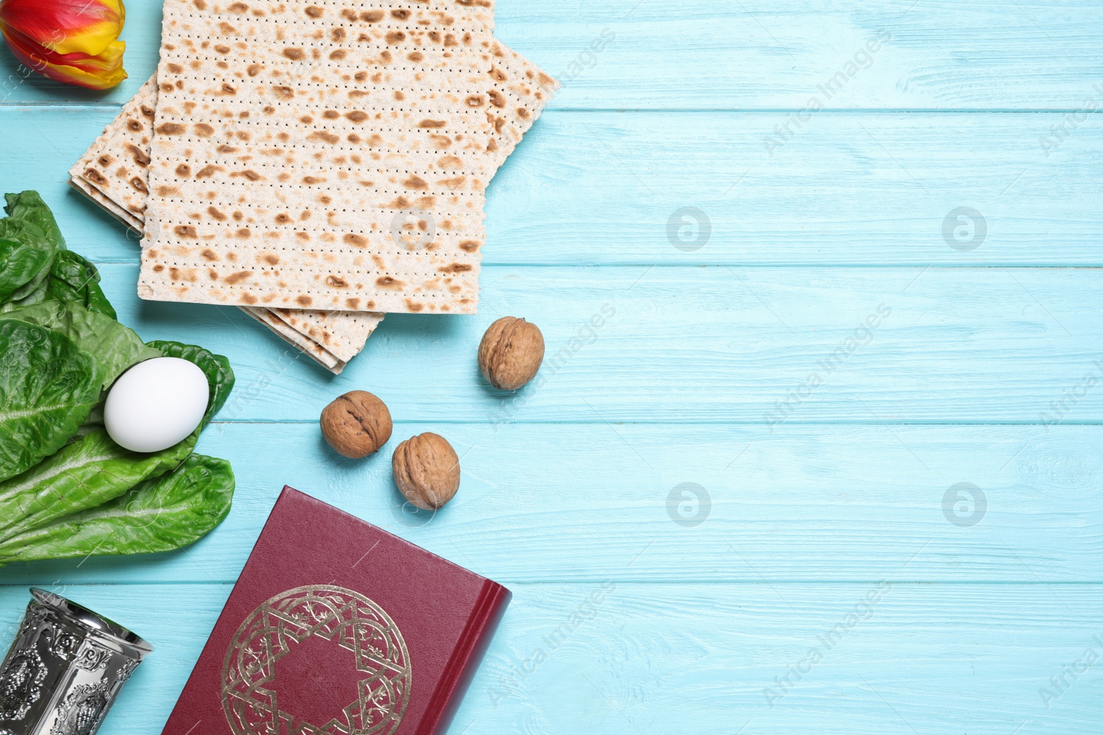 Photo of Flat lay composition with symbolic Pesach (Passover Seder) items on light blue wooden table, space for text