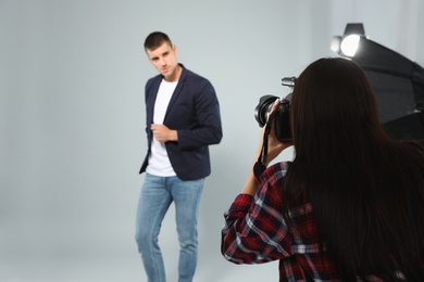 Professional photographer taking picture of young man in modern studio